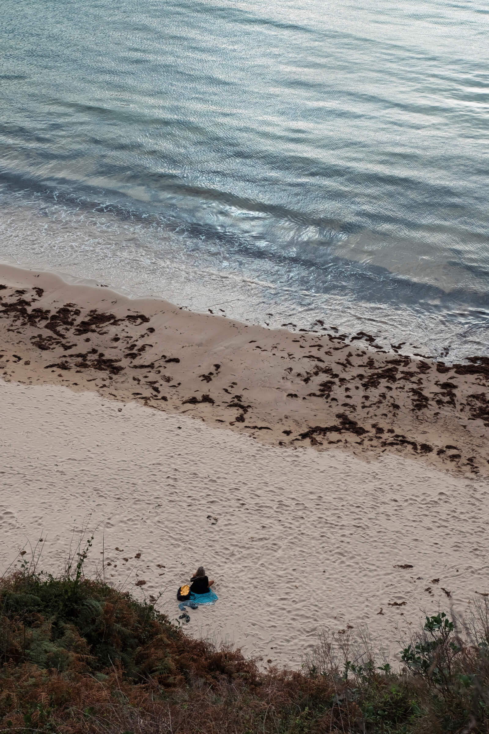 La calma. Playa de Torimbia. Vista de desde arriba de una persona sentada en calma, meditando, en la playa de Torimbia