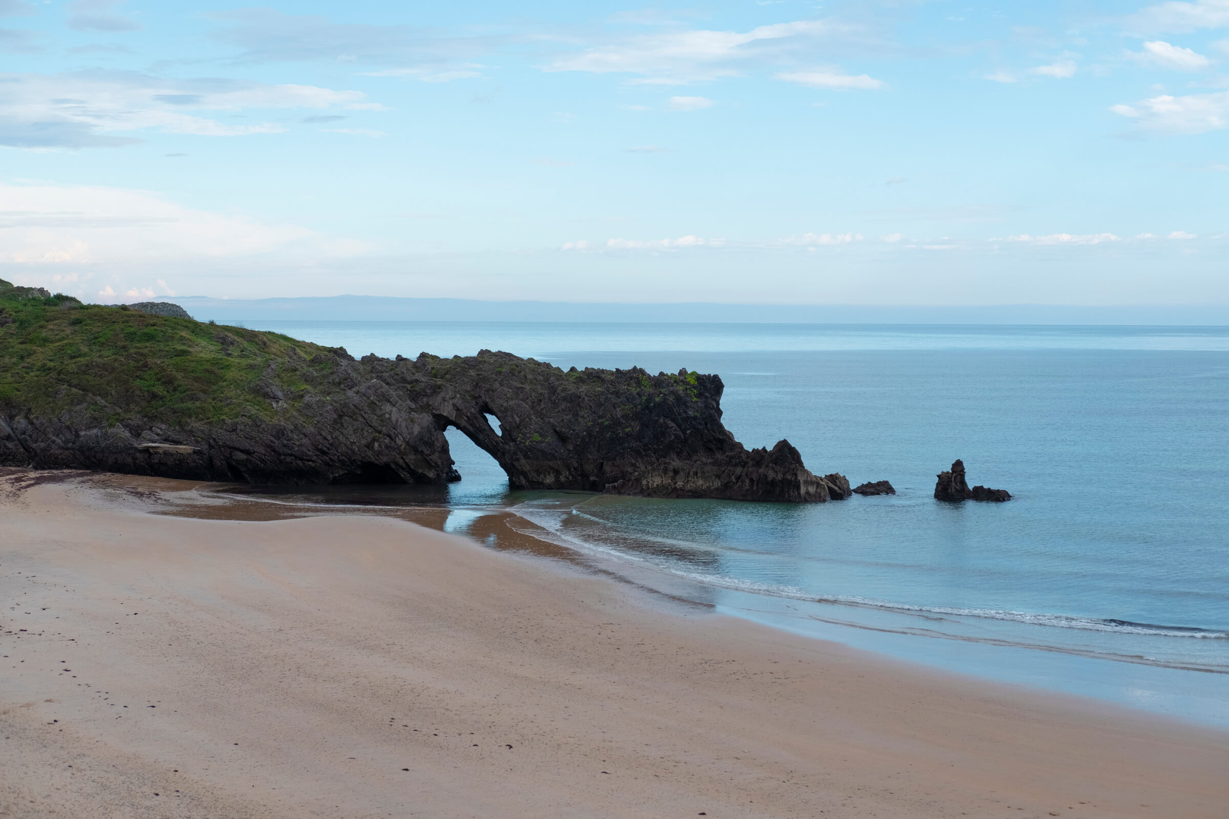 Playa muy lisa con una zona rocosa que forma un arco en el mar