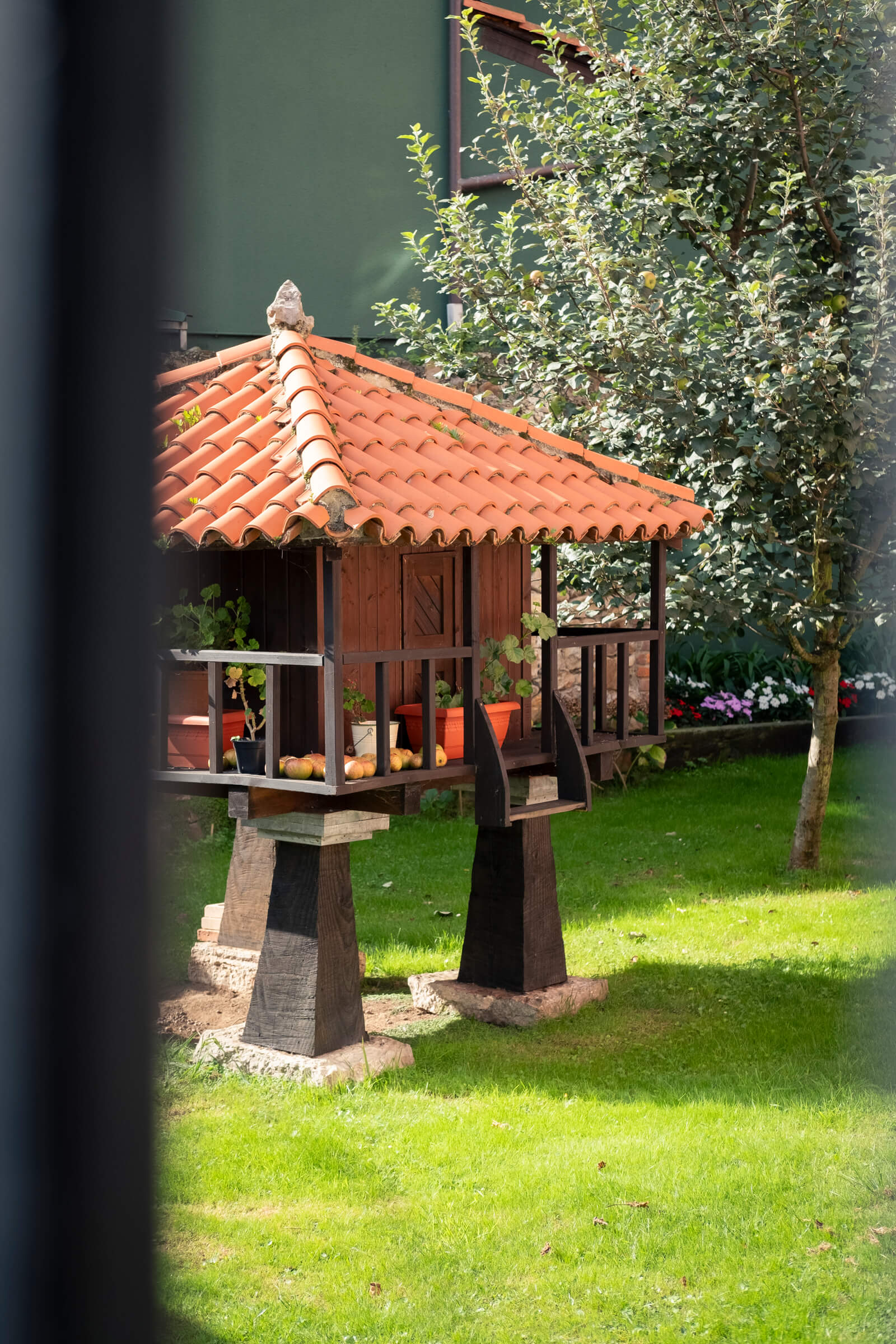 Hórreo en miniatura, transformado en caseta. Hórreo bien mantenido, en el interior de una casa grande y en el jardín con césped verde intenso