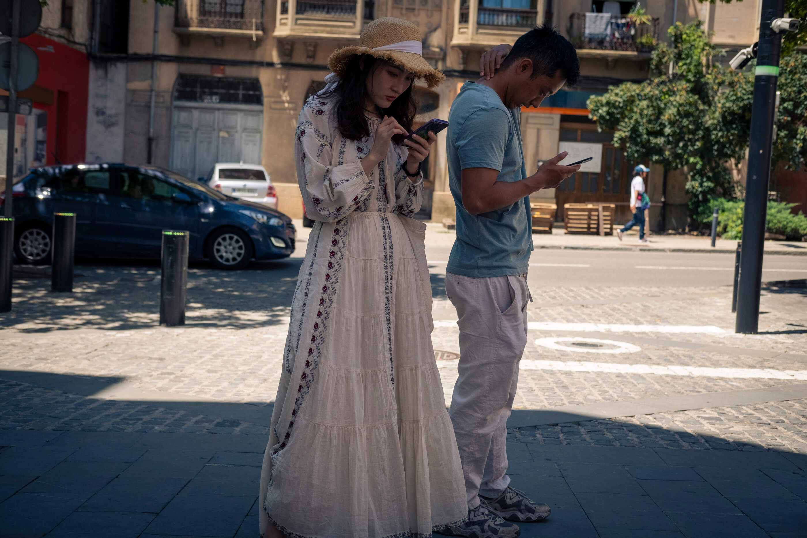 Recalculando ruta. En el medio de la calle, de pie, un chico y una chica - ambos con rasgos orientales - miran sus móviles