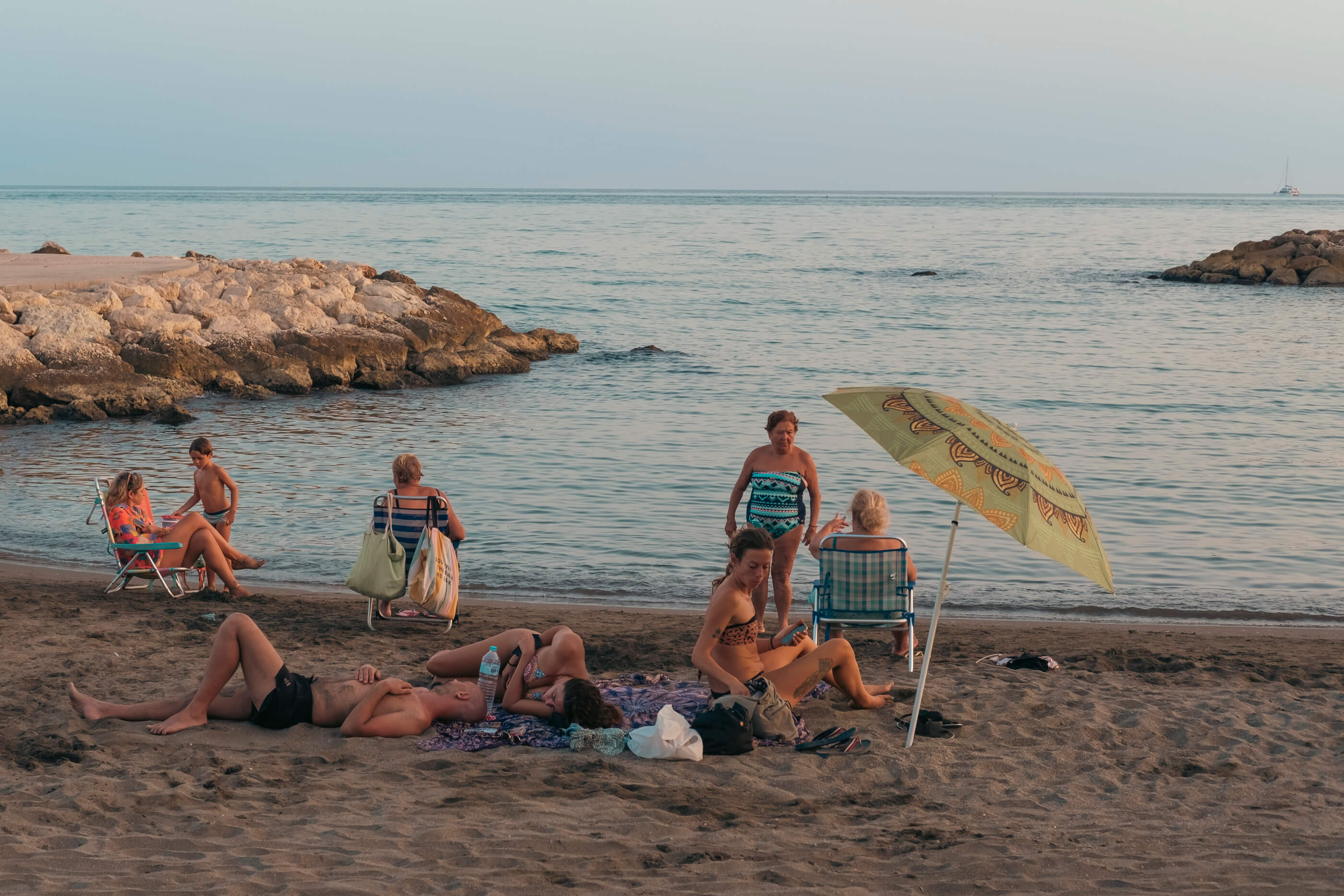 Bodegón veraniego mediterránea. Escena de una playa del Mediterráneo con un grupo de personas tomando el sol y descansando en la arena, a orillas del mar