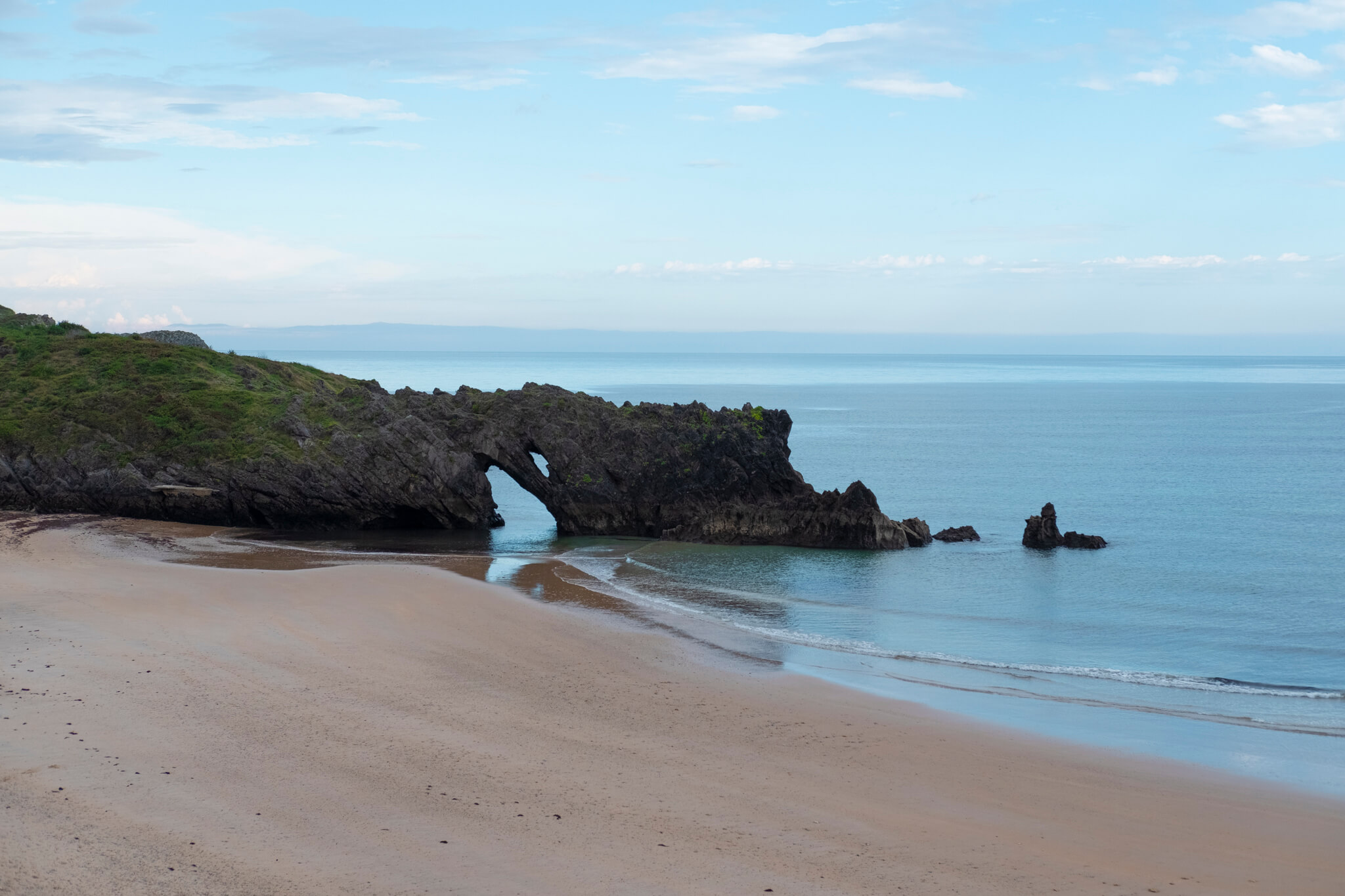 Playa muy lisa con una zona rocosa que forma un arco en el mar