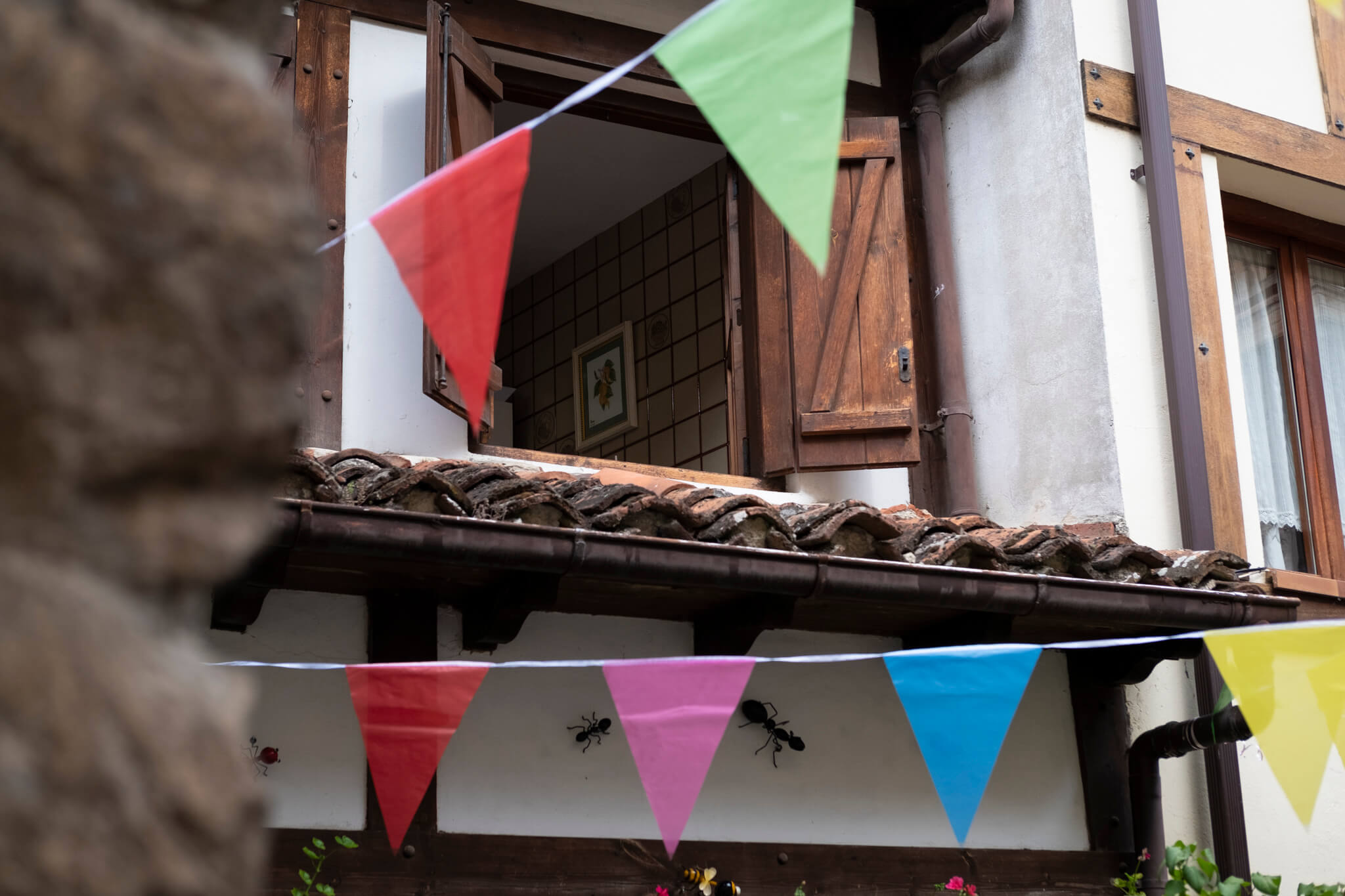 Fiestas hasta la cocina. Una ventana entreabierta de una casa de pueblo deja ver parte de la cocina, con los banderines de fiestas colgados en la calle