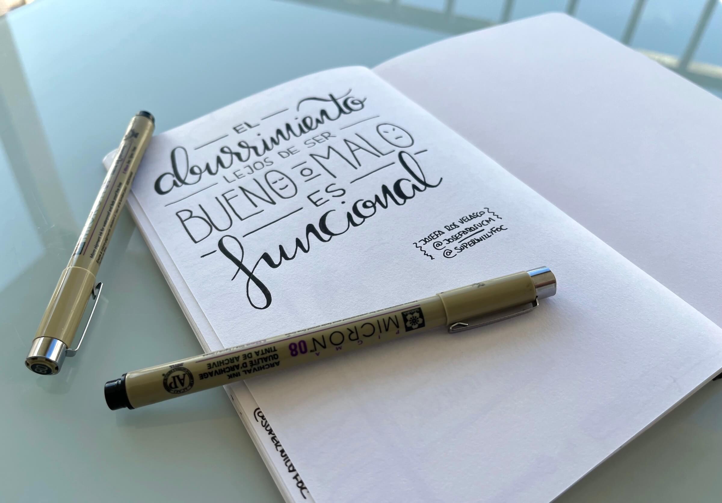 Cuaderno con la cita de Josefa Ros Velasco. Foto del cuaderno sobre la mesa, abierto con la página en la que está manuscrita la cita de la semana, y los rotuladores que he utilizado para dibujarla