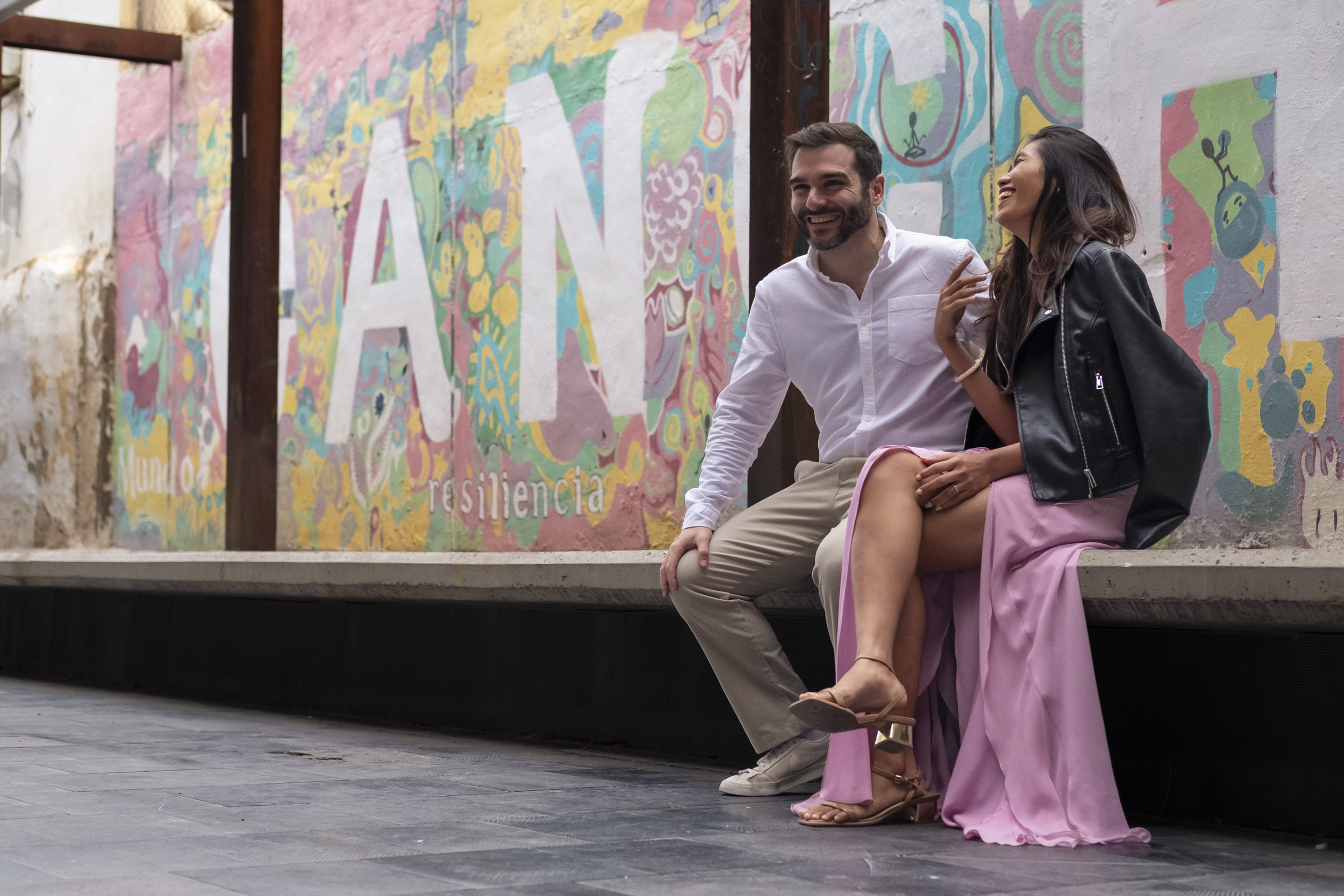 Mis amigos Héctor y Kitt en la plaza de Las Armas. Mis amigos Héctor y Kitt, riéndose, sentados en un banco de cemento un mural muy colorido en la pared de detrás