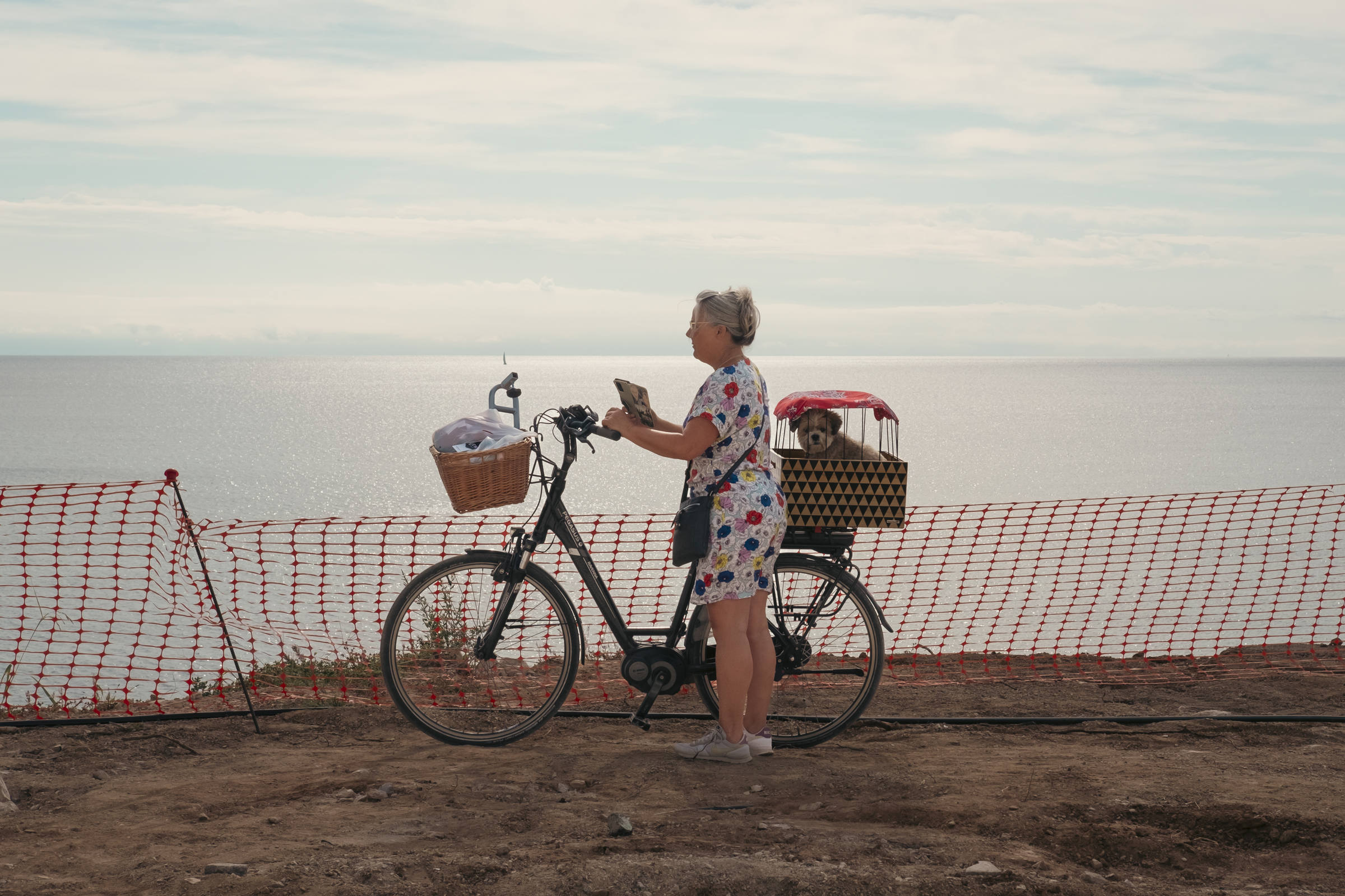 Señora de paseo con su bici y su compi perruno. Señora con la bici parada en el camino y el perrete protegido en un cajón en la parte de atrás de la bici