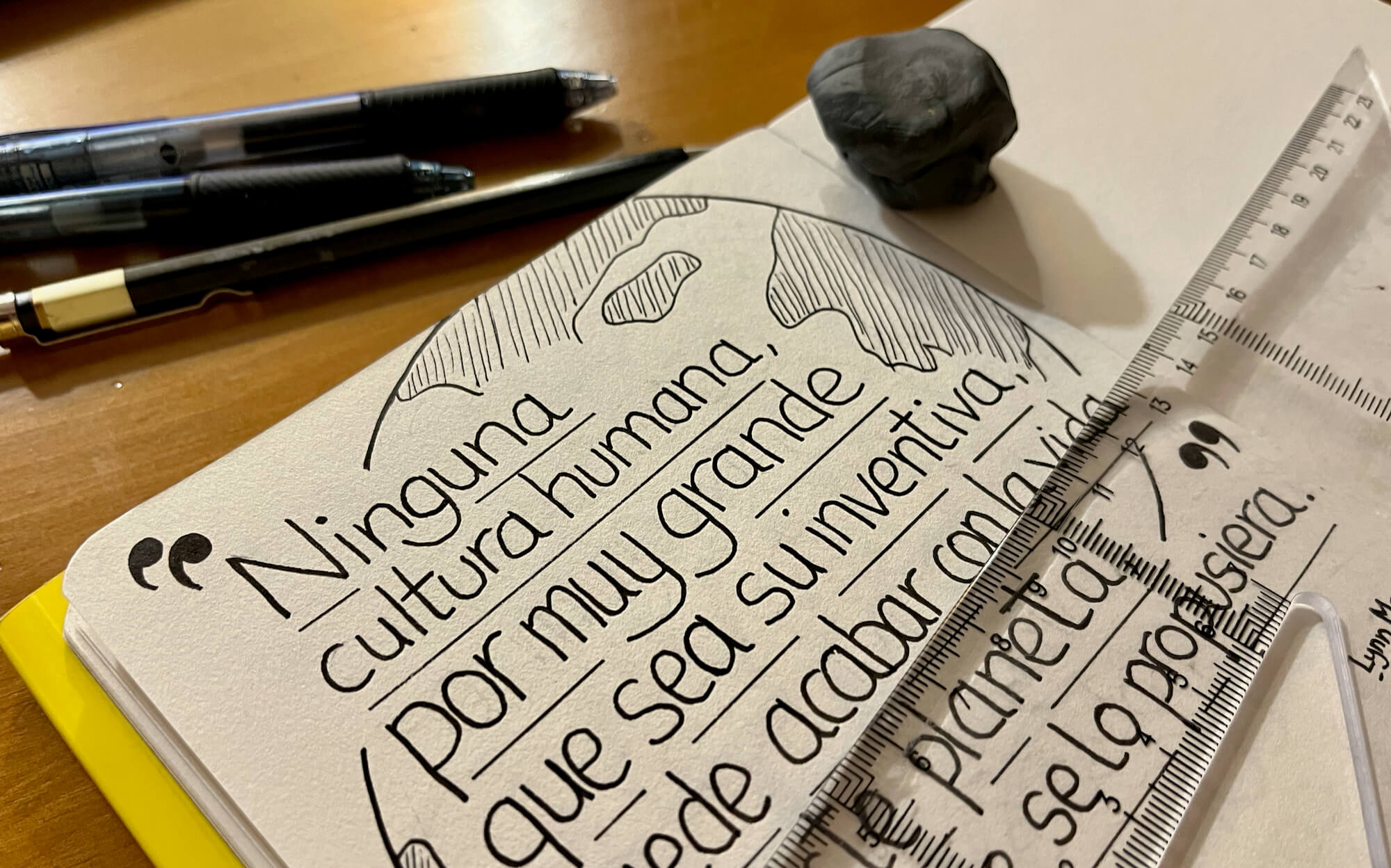 Foto del proceso, escribiendo la cita en el cuaderno. Foto del cuaderno sobre la mesa con la cita a medio escribir