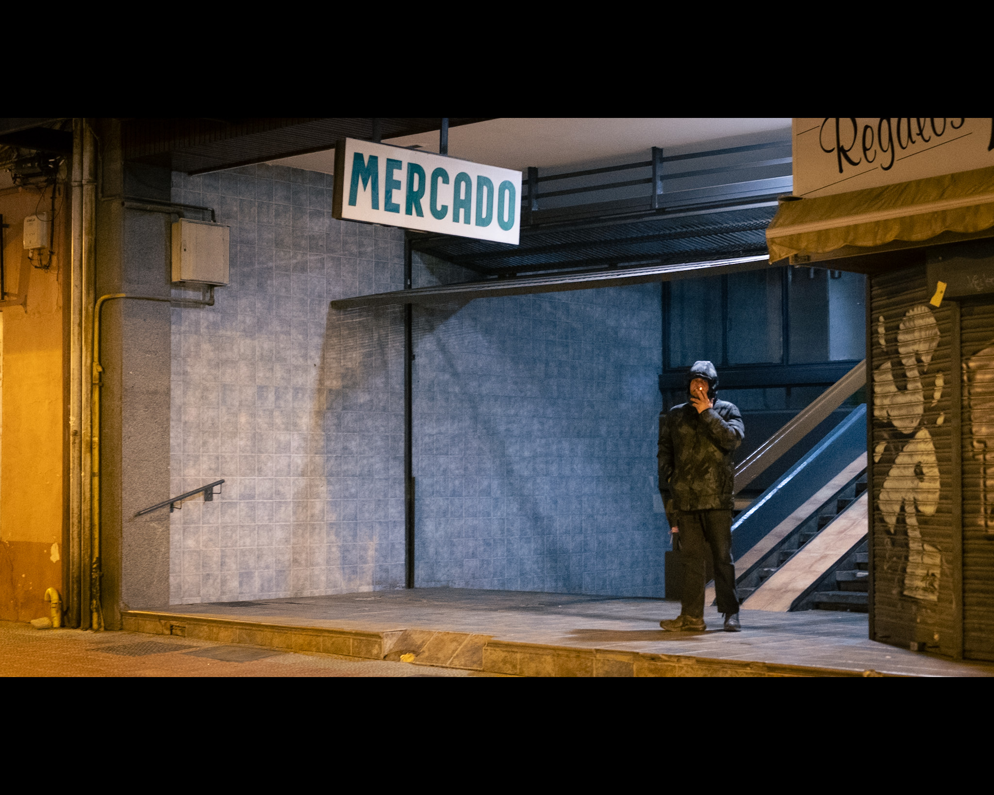 Un chico caminando y fumando en la puerta de un mercado urbano tradicional