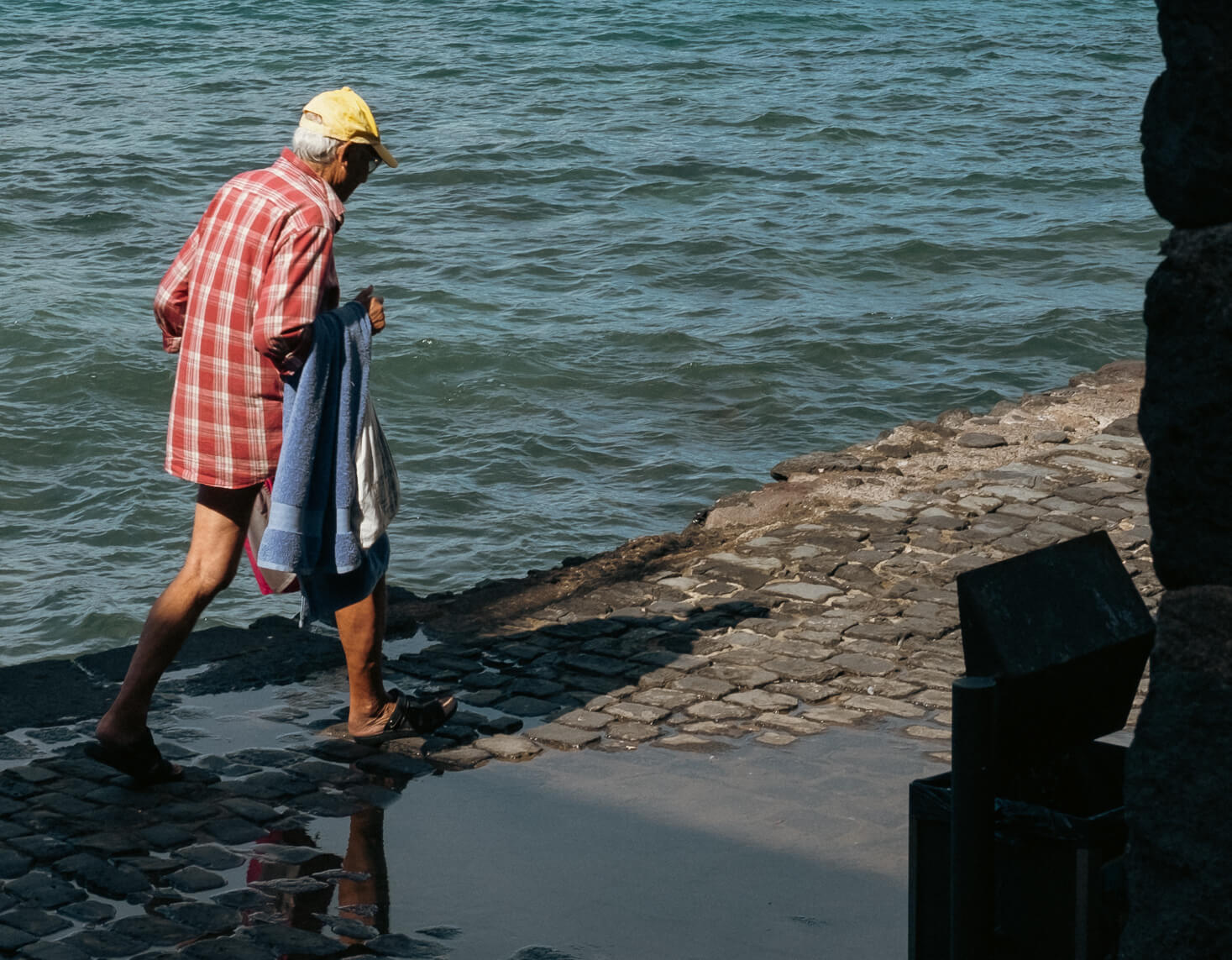 Señor caminando con bañador y toalla de camino a darse un baño en el mar
