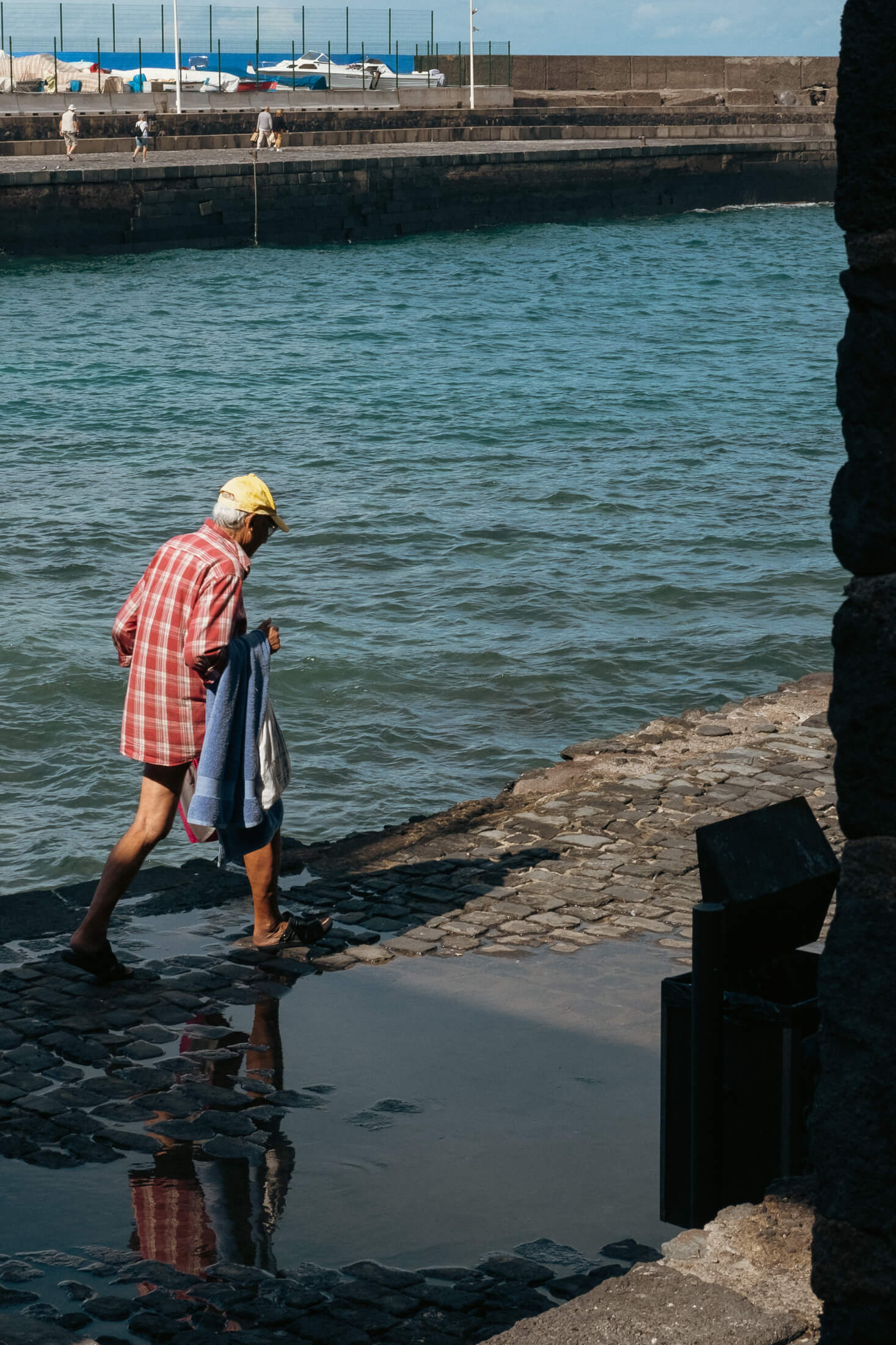 Señor caminando con bañador y toalla de camino a darse un baño en el mar