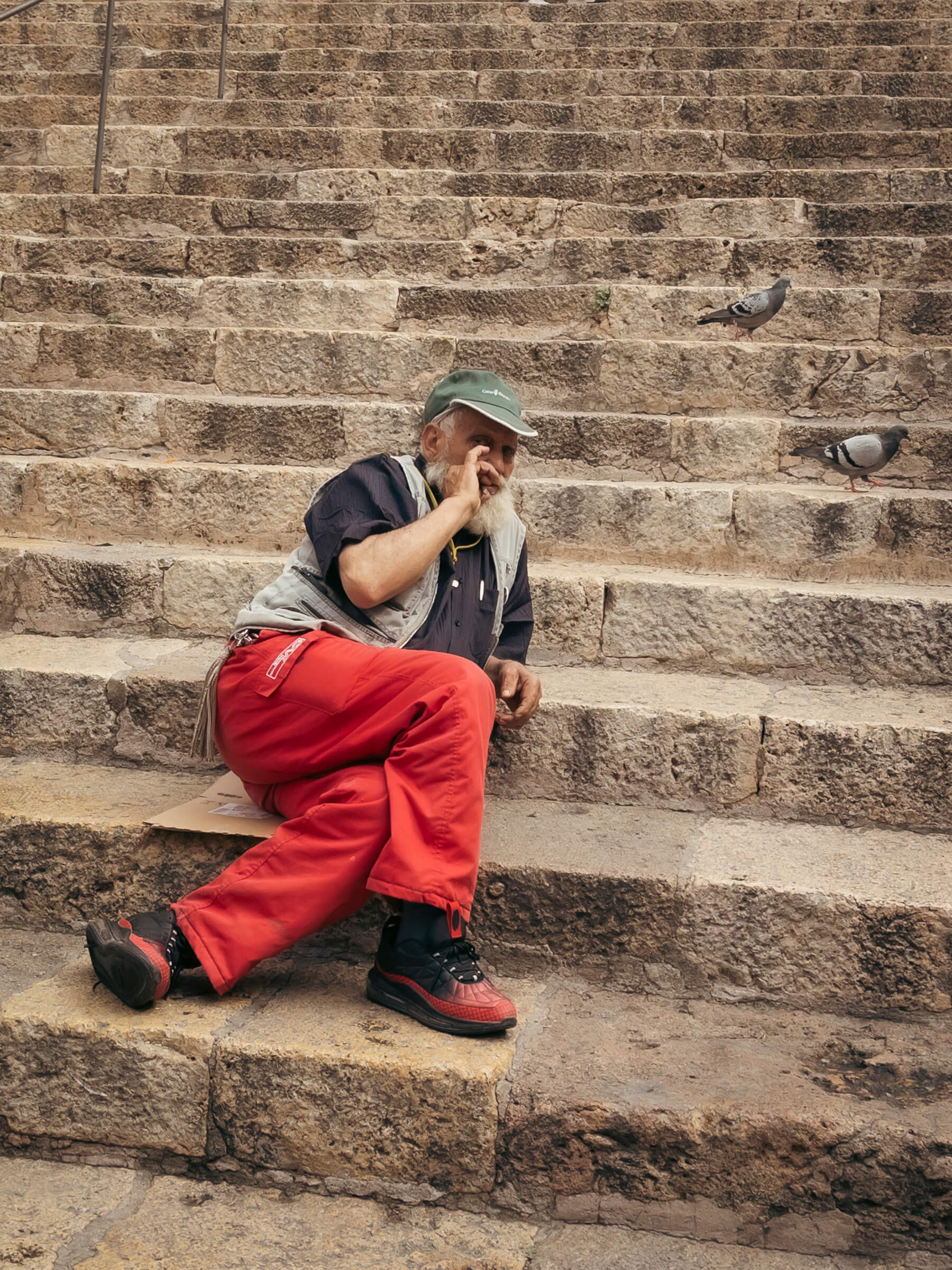 Señor tomándose un respiro (y fumando una faria) en la escalera de la plaza de la catedral de Tarragona. Señor recostado en las escaleras y dando una calada al puro con unas palomas a su lado