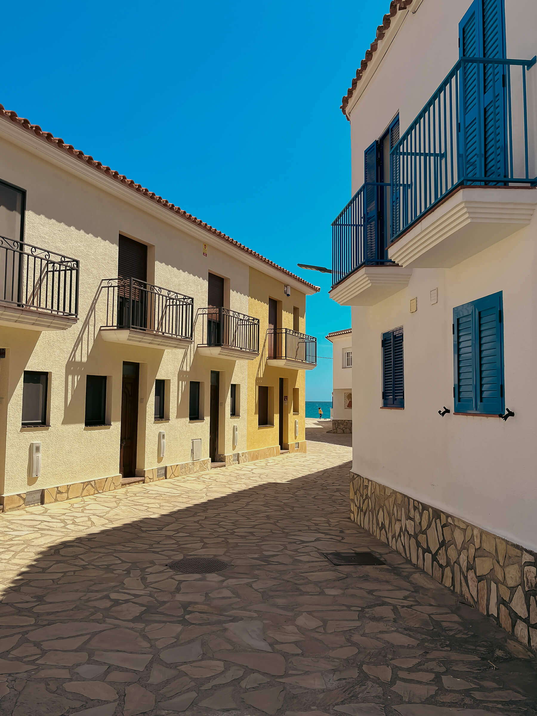 Calles en zig-zag llevando al mar. Parque Mont-Roig (Tarragona). Foto de una calle que parece hecha en zigzag, con iluminación de mediodía y el mar de fondo.