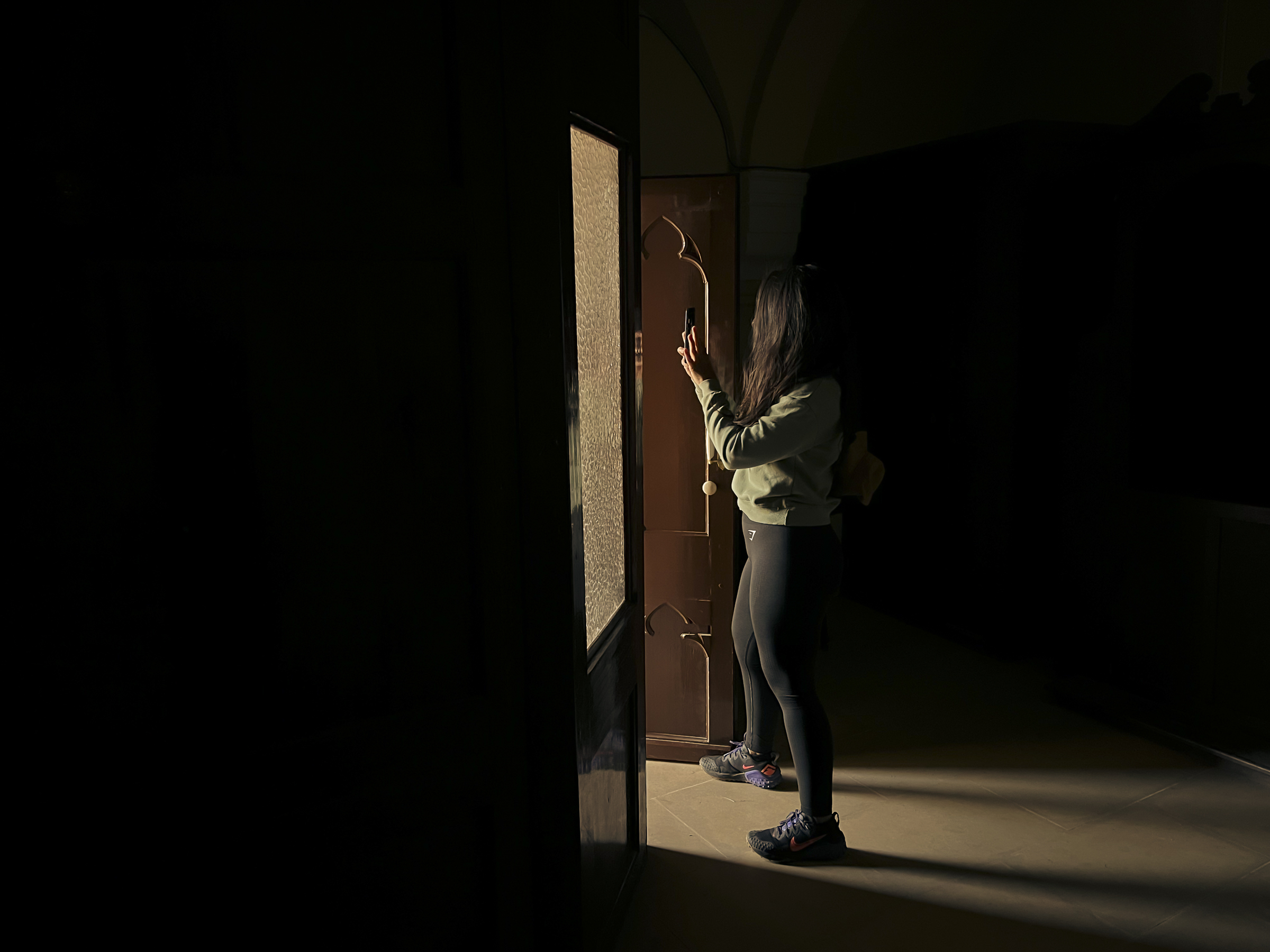 Laura haciendo una foto con el móvil, desde dentro de la ermita y enfocando al exterior, con la luz iluminándola.