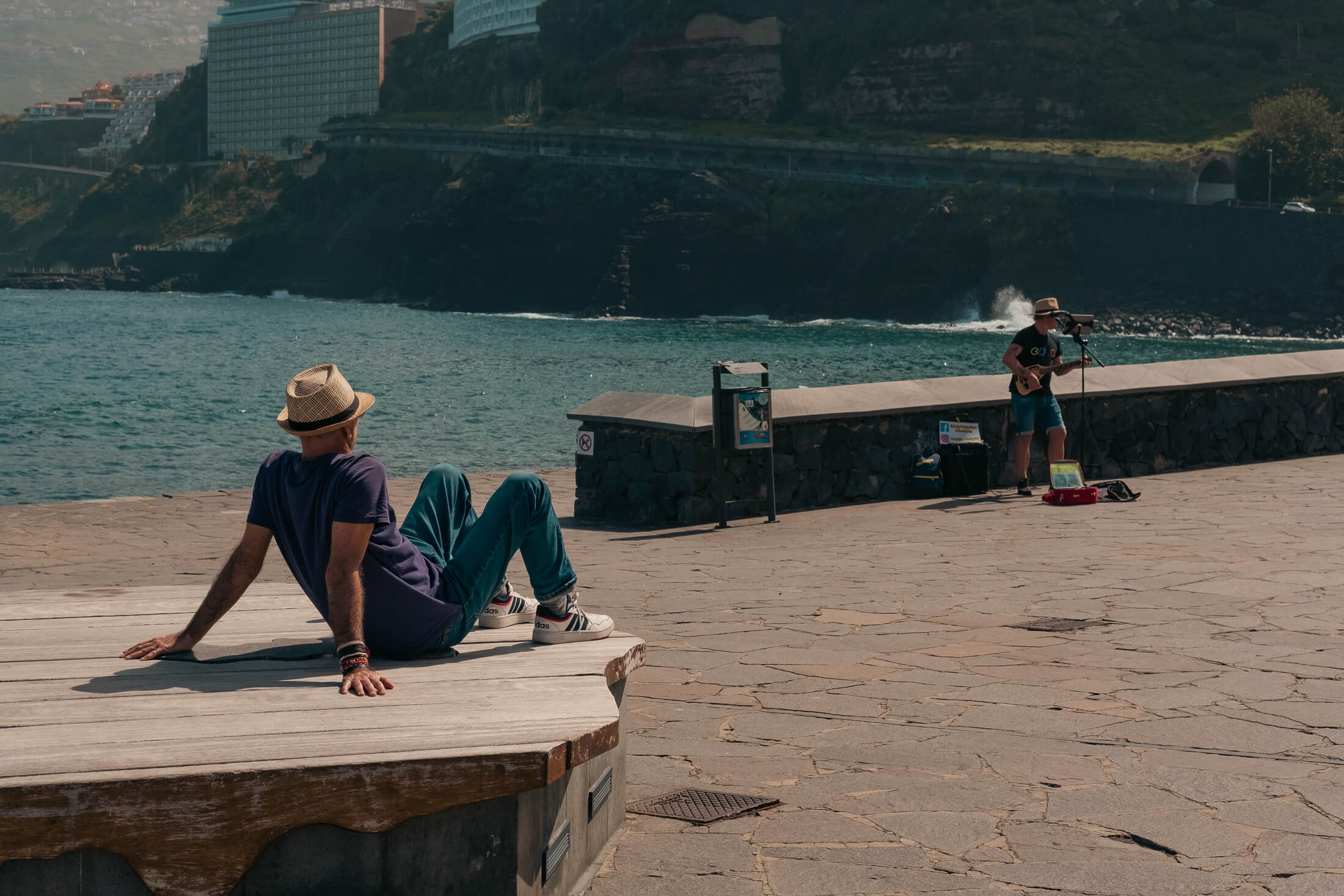 Un chico toma el sol del atardecer mientras escucha música en directo en la playa