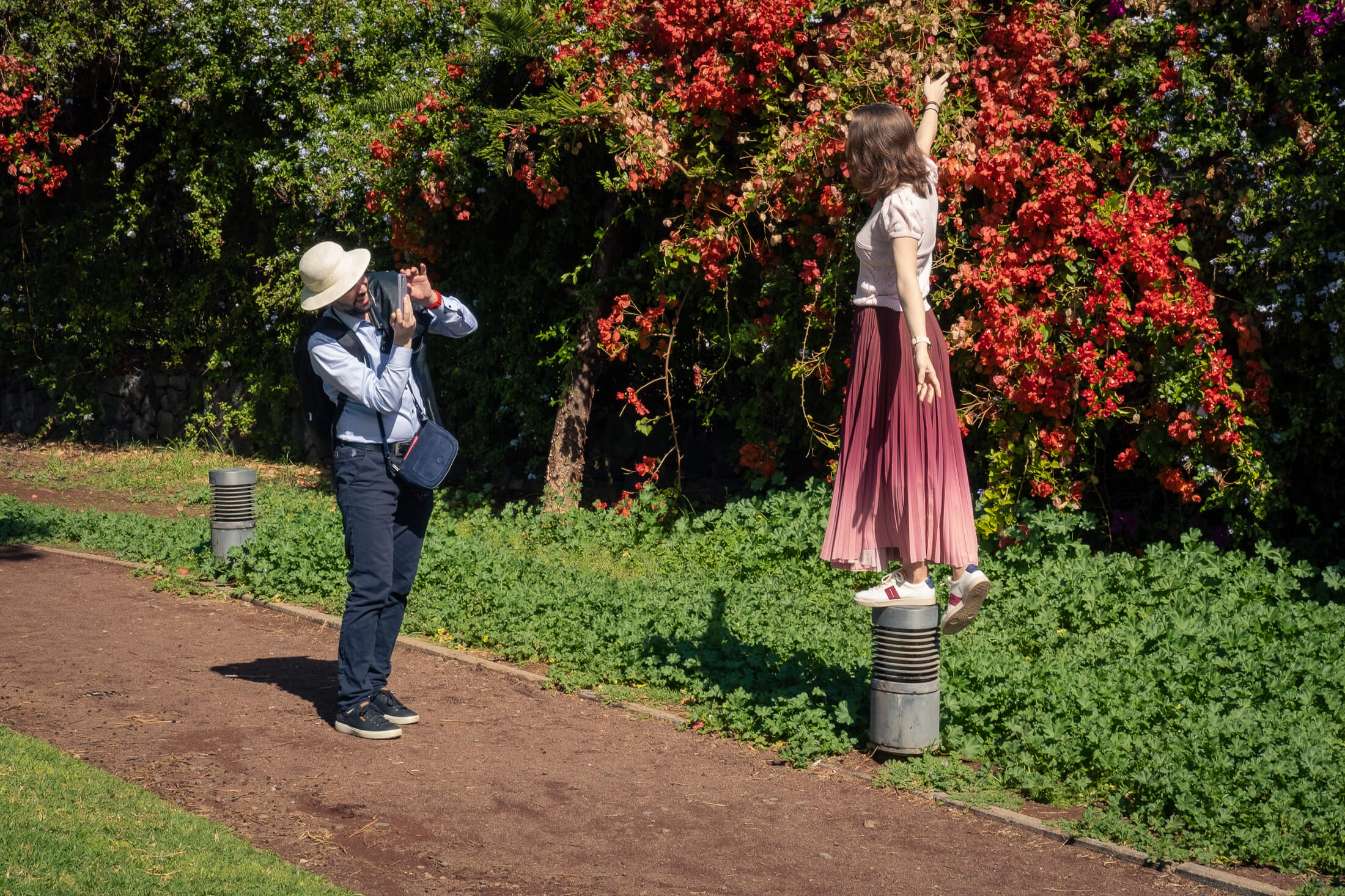 Foto de una chica posando y su pareja haciéndole una foto con la buganvilla de fondo