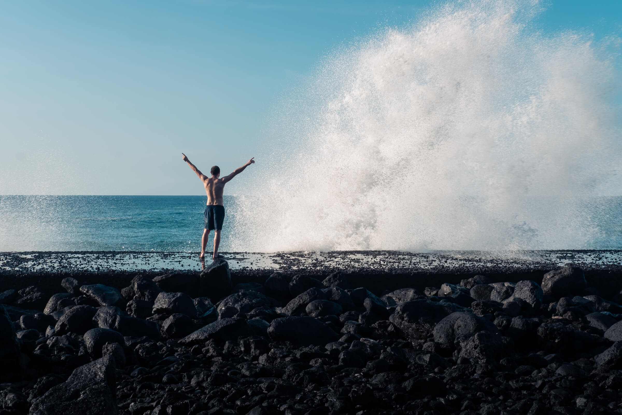 Un hombre aprovechando la fuerza de las olas para tomar una ducha natural. Fotografía del oleaje del Atlántico