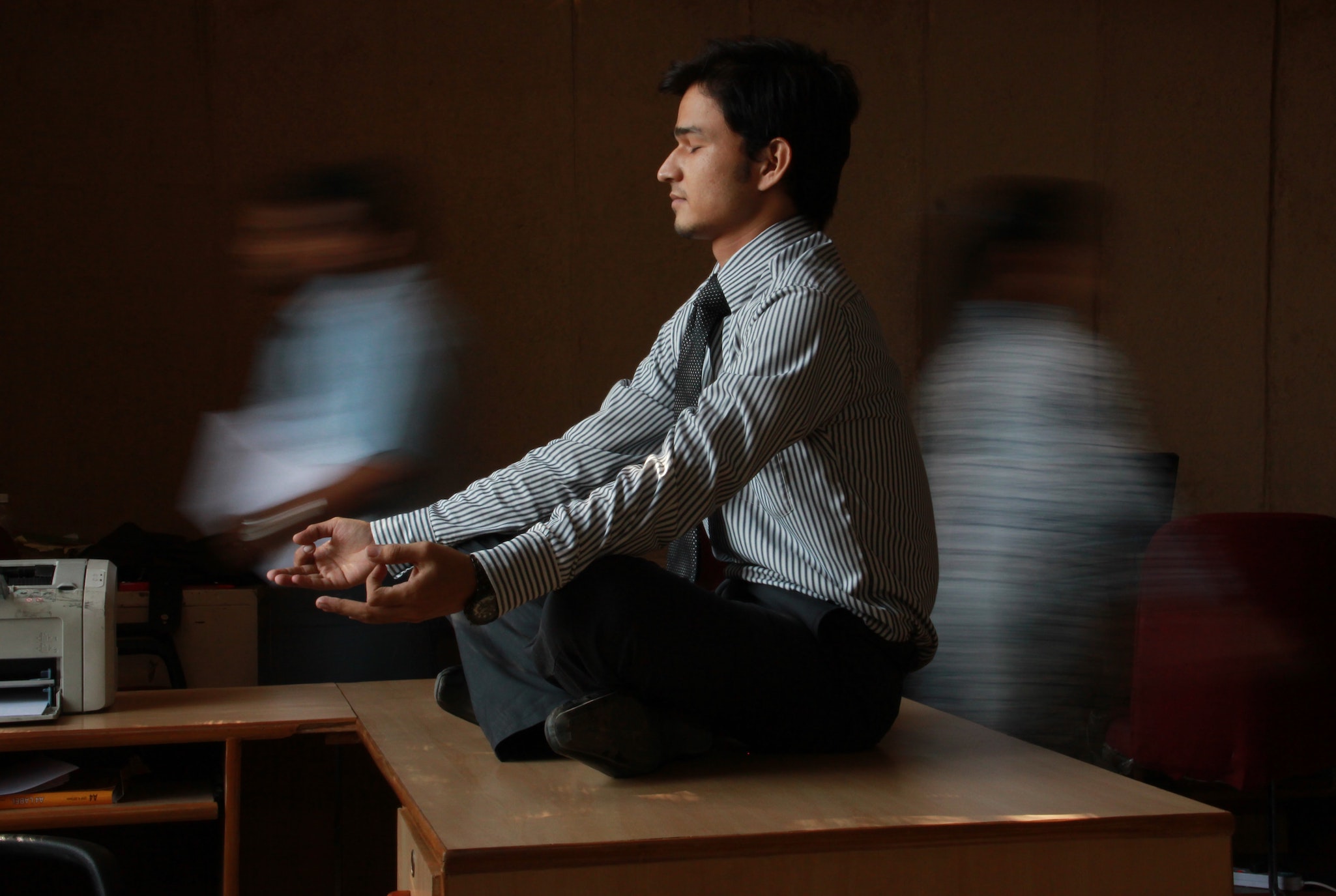 Señor meditando sentado en su escritorio de trabajo y vestido con traje y corbata